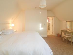 ein Schlafzimmer mit einem großen weißen Bett und einem Schreibtisch in der Unterkunft Robertson's Cottage in Caledon