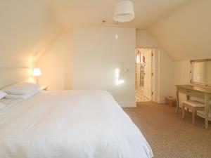 a bedroom with a large white bed and a desk at Robertson's Cottage in Caledon