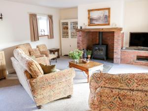 a living room with two couches and a fireplace at Grange Cottage in Crediton