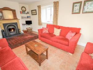 Goose Cottage في Caledon: غرفة معيشة مع أريكة حمراء ومدفأة