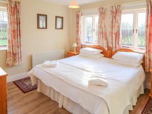 a bedroom with a large white bed and windows at Goose Cottage in Caledon