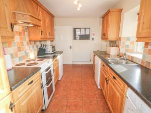 a kitchen with wooden cabinets and an orange tile floor at Goose Cottage in Caledon