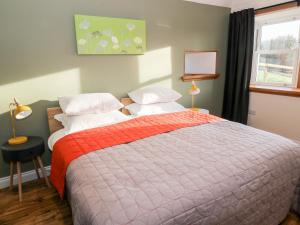a bedroom with a large bed and a window at Glebe Cottage in Dumfries