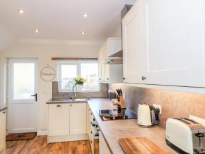 a kitchen with white cabinets and wooden floors at Glebe Cottage in Dumfries +15 photos