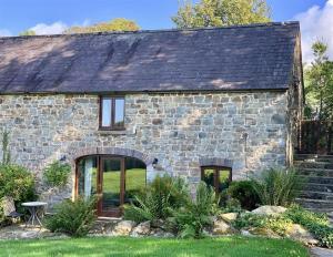 uma casa de pedra com portas de vidro e um quintal em Stable Cottage em Newport