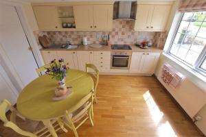 a kitchen with a table with a vase of flowers on it at Beach Retreat in Aberporth