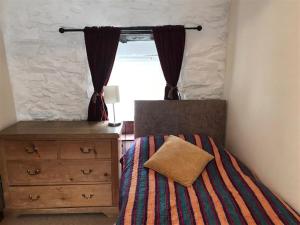 une chambre avec un lit, une commode et une fenêtre dans l'établissement Beach Cottage, à Little Haven