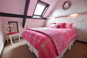 um quarto com uma cama rosa e uma janela em 5 The Coach House em Haverfordwest