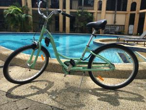 een groene fiets geparkeerd naast een zwembad bij Oasis Inn Apartments in Cairns