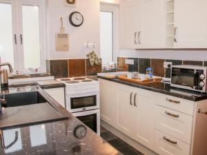 a kitchen with white cabinets and a stove top oven at Hightree Lodge Barn in Craven Arms