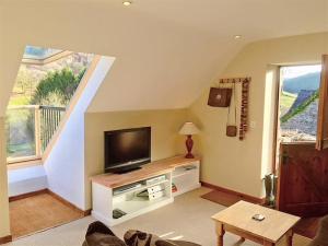 a living room with a flat screen tv on a table at Upper Barn Cottage in Aberangell