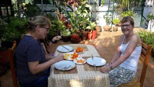 Duas mulheres sentadas à mesa a comer comida. em Jojies Homestay Fortkochi em Cochin