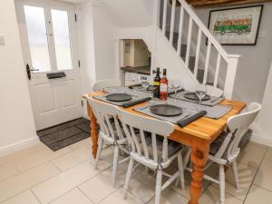 a dining room with a wooden table and white chairs at Rose Cottage in Grange Over Sands