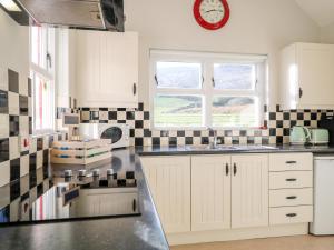 een keuken met witte kasten en een klok aan de muur bij Katies Cottage in Newry