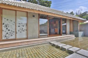 a house with large glass windows on the side of it at KAWASEMINOSU (MUKAKA VILLA) in Nago