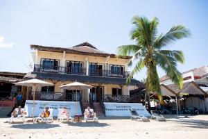 a group of people sitting on the beach in front of a hotel at Hotel-Residence Au Sable Blanc in Madirokely