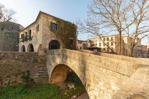 un vieux pont en pierre avec un bâtiment en arrière-plan dans l'établissement Bravissimo Sacsimort, à Gérone