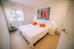 een slaapkamer met een groot wit bed met oranje kussens bij Amazing penthouse at La Fosca beach in Palamós