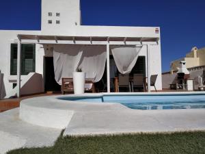 a swimming pool in front of a house at Aloha Surf House in Corralejo