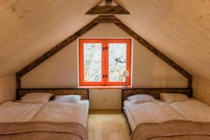 two beds in a room with a window at Nebo nad Štiavnicou - oranžová chalupa na okraji lesa in Banská Štiavnica