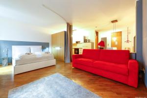salon z czerwoną kanapą i łóżkiem w obiekcie Laubenapartment w Meranie