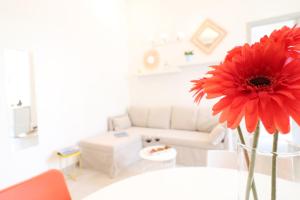 un fiore rosso in un vaso su un tavolo in un soggiorno di Casa Vacanze aura a Otranto 4 posti a Otranto