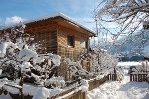 una cabaña de madera en la nieve con una valla en Landhaus Neussl en Kaltenbach