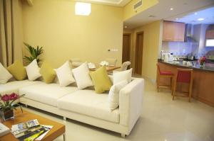 a living room with a white couch and a kitchen at Grand Bellevue Hotel Apartment Dubai in Dubai
