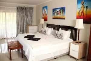 a bedroom with a large bed with white sheets at Tinyiko Kruger Lodge in Marloth Park