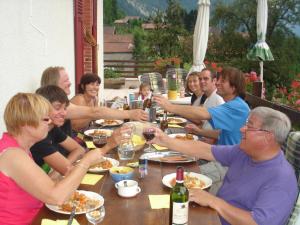 um grupo de pessoas sentadas em torno de uma mesa bebendo vinho em L'Horizon des Alpes em Le Petit-Bornand-lès-Glières