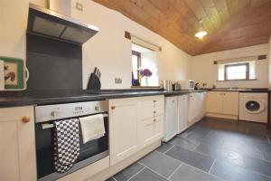 a kitchen with white cabinets and a black counter top at Panteurig Farmhouse in Goodwick