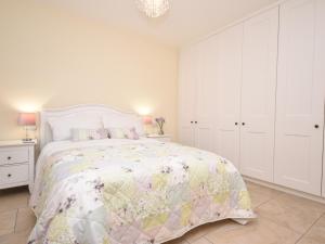 a white bedroom with a bed and white cabinets at Lavender Cottage in York
