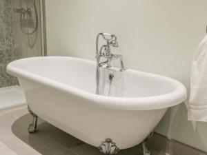 a white bath tub with a faucet in a bathroom at Lavender Cottage in York +12 photos