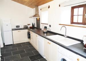 uma cozinha com armários brancos e um lavatório em Panteurig Cottage em Goodwick