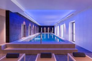 a swimming pool in a building with blue tiles at Hotel du Roi & Spa by SOWELL COLLECTION in Carcassonne