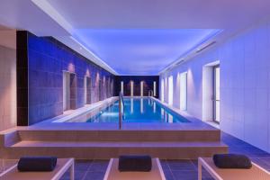 una piscina en un edificio con azulejos azules en Hotel du Roi & Spa by SOWELL COLLECTION, en Carcassonne