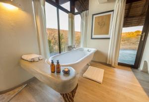 a bathroom with a sink and a large window at Impodimo Game Lodge in Madikwe Game Reserve