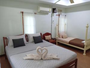 two swans towels on two beds in a bedroom at Rai Lung Tui Homestay in Prachuap Khiri Khan