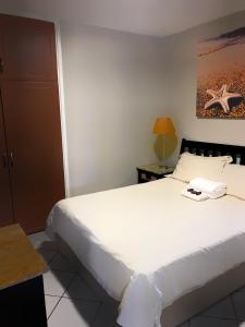 Un dormitorio con una cama blanca con un teléfono. en LA Ballito, en Ballito