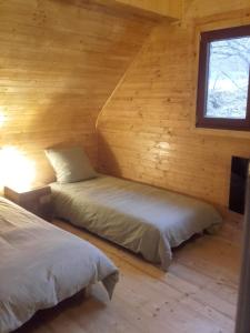 two beds in a log cabin with a window at Le chalet de Magali in Briançonnet