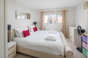a bedroom with a large white bed with red pillows at ALTIDO Charming 2-bed flat in Kensington, nearby tube in London