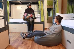 uma mulher sentada no chão num quarto com beliches em The Blue Jay Hostel - Dorms & Rooms em Rishikesh