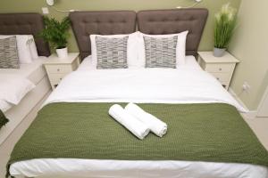 a bed with two white towels on a green blanket at The Spinney in Bracknell