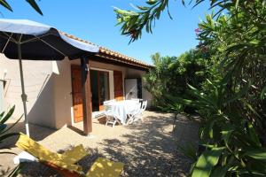 une terrasse avec une table, des chaises et un parasol dans l'établissement Belle villa climatisée 5 couchages belle terrasse ombragée parking dans résidence sécurisée piscine commune à 400m de la mer LRJP23, à Portiragnes