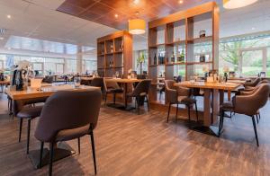 a restaurant with wooden tables and chairs and windows at Fletcher Hotel Restaurant Beekbergen-Apeldoorn in Beekbergen