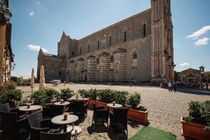 a courtyard with tables and chairs in front of a building at Duomo Luxury Apartment Orvieto in Orvieto