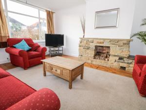 a living room with two red chairs and a fireplace at Sea Dreams in Worthing