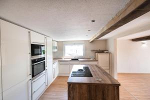 a kitchen with white cabinets and a wooden table at SOVA Pension Baunatal in Baunatal