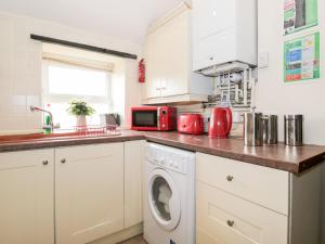 a kitchen with a washing machine and a microwave at Combe Cottage in Stroud