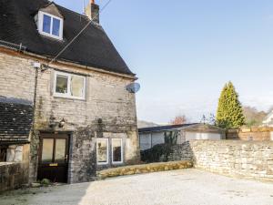 an old stone house with a driveway in front of it at Combe Cottage in Stroud